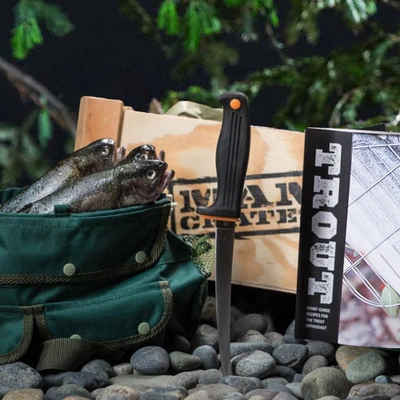 The Troutdoorsman Crate includes recipe book, fish seasoning, canvas creel, filet knife, and grill holder.