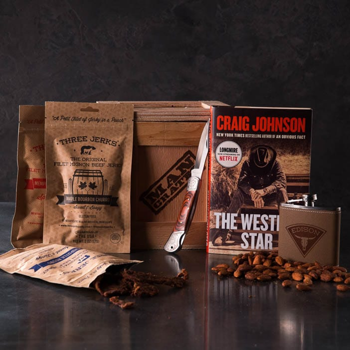 Storied Western Cocktail Crate includes a Longmire novel by Craig Johnson, personalized flask, an assortment of jerky, lockback pocketknife, and almonds.