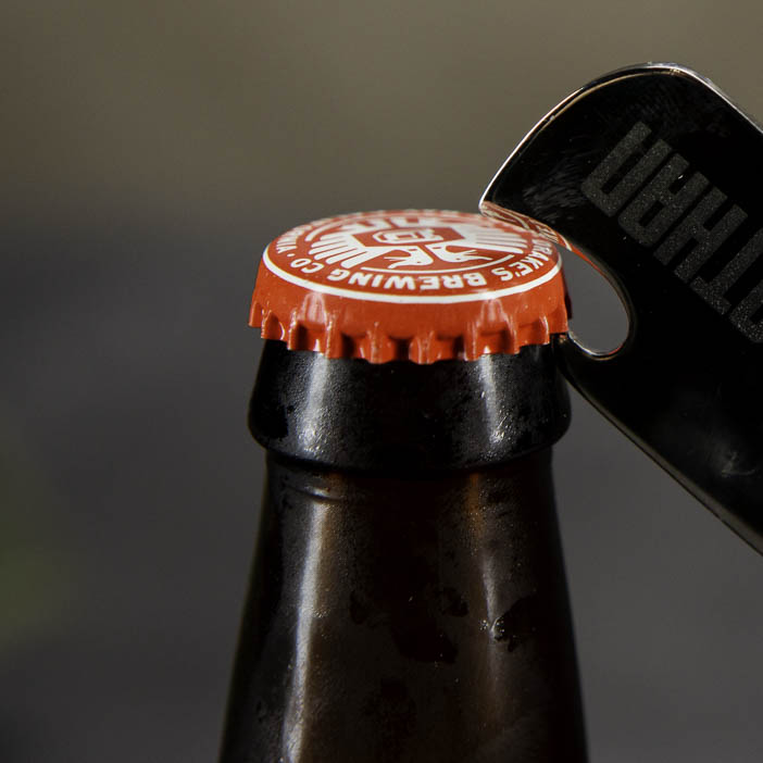 dog tag bottle opener opening a bottle
