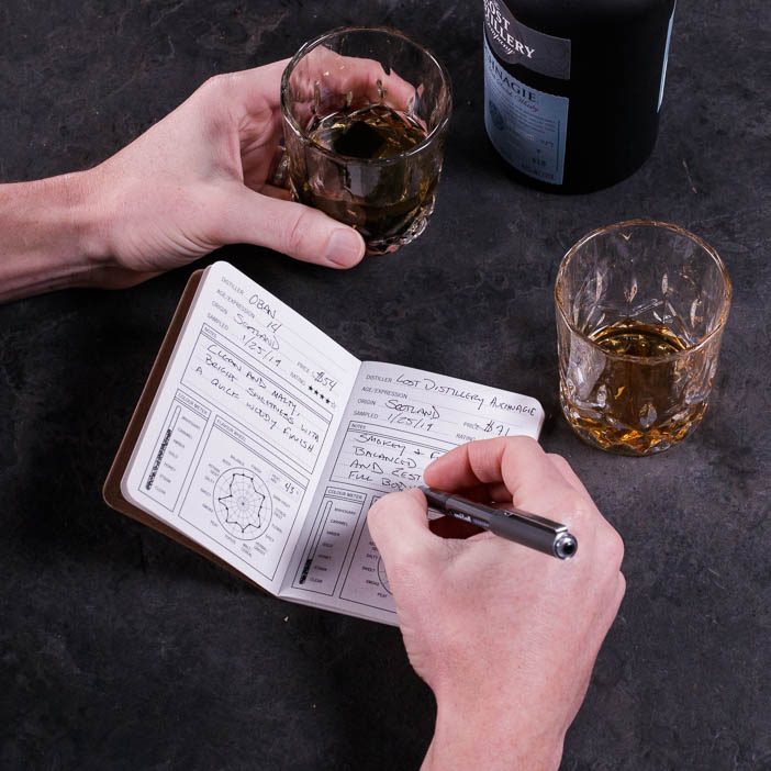 Man writing in Tasting Journal while holding a full glass is a great men's drink gift.
