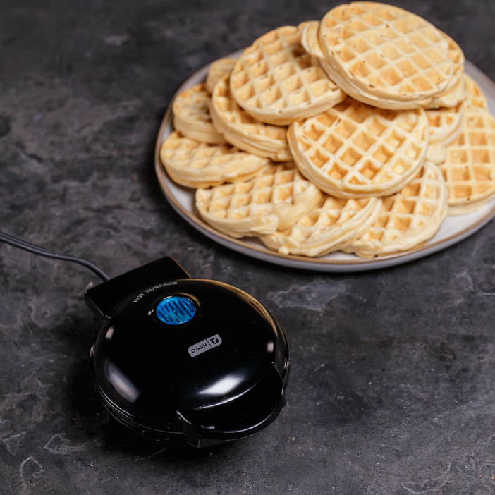Closed waffle maker and a plate of waffles for a great men's cooking gift.