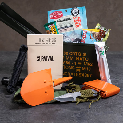 Outdoor Survival Ammo Can includes collapsable shovel, paracord, knife, firestarter, survival field manual, survival blanket, glow stick, and assorted snacks.