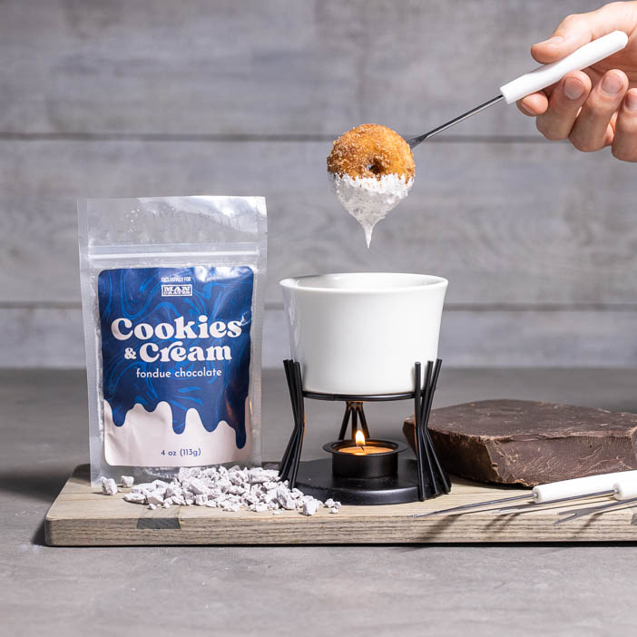 Donut being dipped into cookies and cream frosting is a great men's cooking gift.