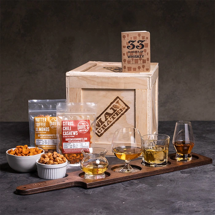 Whiskey glasses on paddle, nuts in bowls, journal, and a crate for a great men's whiskey gift.