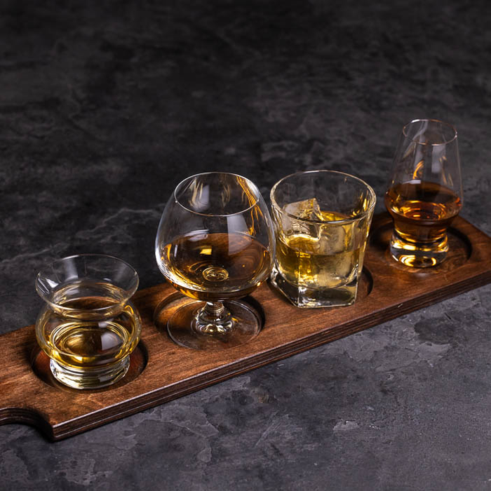 Four different whiskey glass on serving paddle for a great men's whiskey gift.